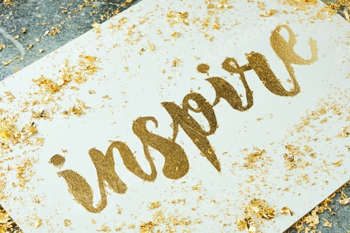 Preview: Inspire. Motivating lettering on white board. Handmade creativity. Gold letters. Gilding.