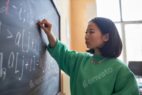 Preview: Young serious teacher or student of highschool writing down formulas