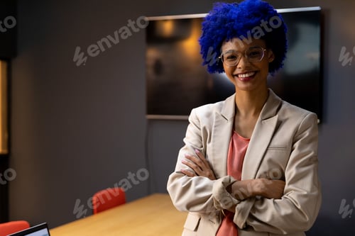 Preview: Portrait of happy biracial casual businesswoman with blue afro smiling in office