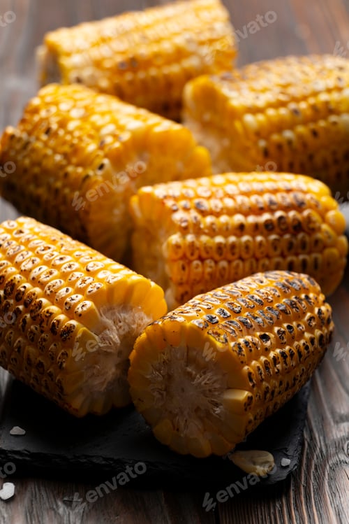 Preview: Slate tray with Pieces of Grilled corn on the cob on kitchen table healthy food background
