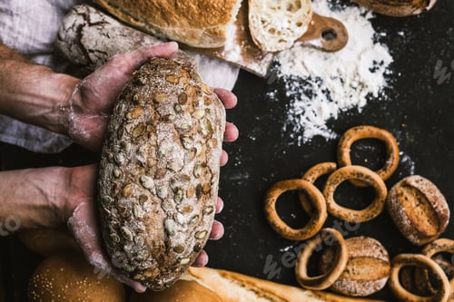 Preview: Baker man holding a rustic organic loaf of bread in his hands