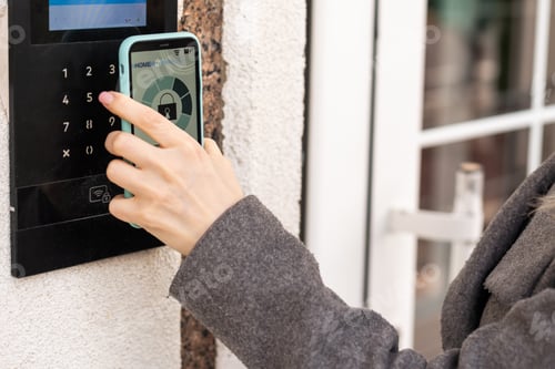 Preview: Woman touching smartphone to intercom at office.