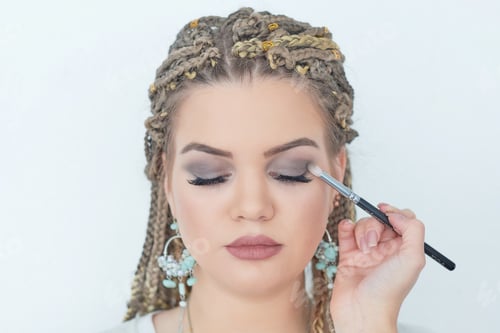 Preview: Professional makeup artist working with beautiful young woman. bright blonde model