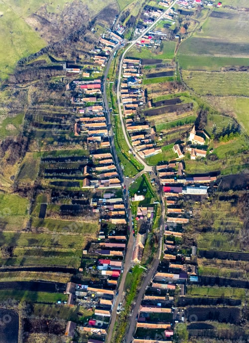 Preview: Aerial view of a picturesque village in Romania surrounded by lush green hills.