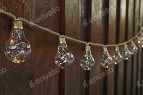 Preview: Garland of lamp bulbs hanging on wooden wall. String lights