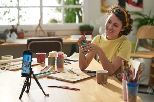 Preview: Young smiling creative woman with paintbrush and gouache during masterclass