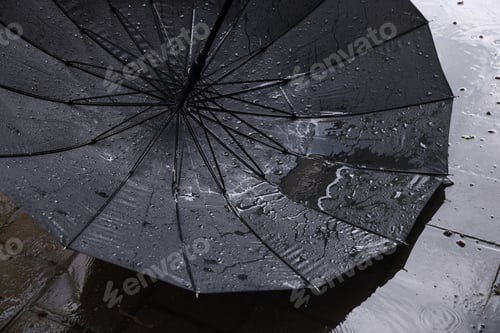 Preview: Black umbrella on wet asphalt under heavy rain, closeup