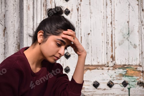 Preview: Young teenage girl sitting by old building thinking about problems feeling sad depressed and alone