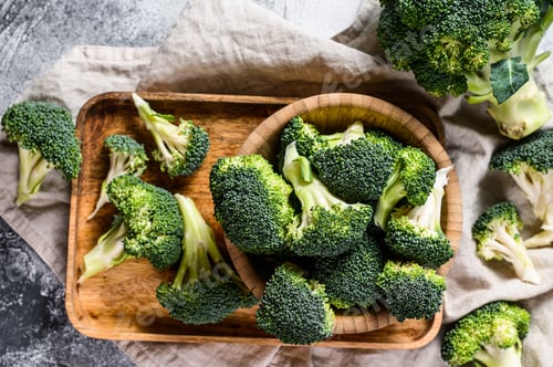 Preview: Raw broccoli in a wooden bowl. Gray background. Top view