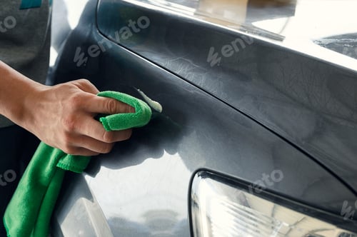 Preview: Man cleaning scratch on car with microfiber cloth and cleaner remover