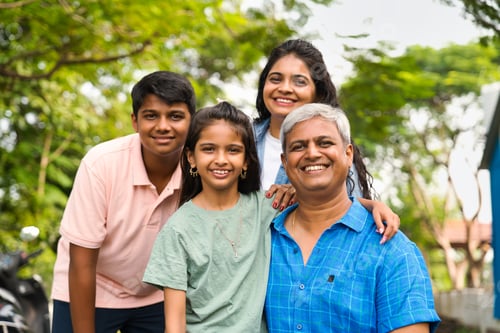 Preview: Indian Asian parents in their forties with two kids, posing outdoors for a family portrait