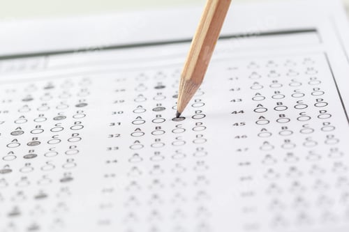 Vista previa: Student marks answer sheet with pencil during exam in classroom setting