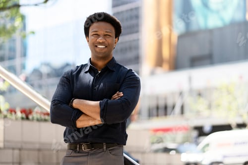 Preview: Confident businessman smiling with arms crossed in city