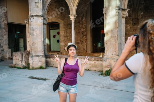 Preview: Young woman posing for photo making peace sign in front of ancient building