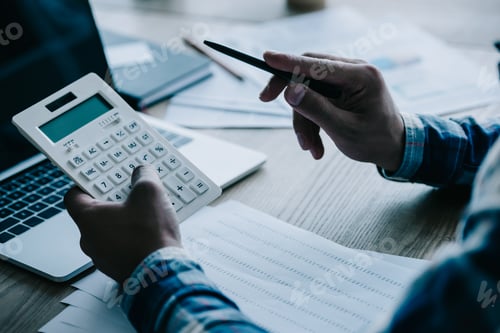 Preview: cropped shot of businessman with calculator working at workplace with documents and laptop