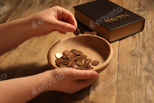 Preview: Donate and give concept. Woman putting coin into bowl at wooden table, closeup