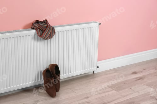 Preview: Heating radiator with scarf and shoes near color wall, Space for text