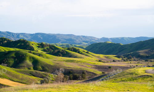 Preview: Scenic view of rolling green hills under blue sky.