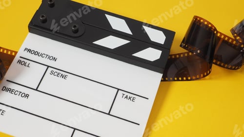 Preview: Small white clapper board and film roll on yellow background. It use in movie and video production.