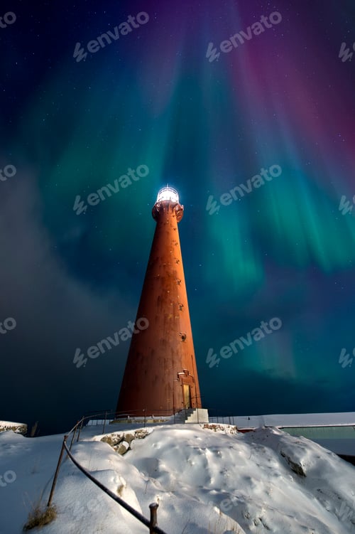 Preview: A majestic lighthouse stands tall under a breathtaking aurora display on a snowy evening.