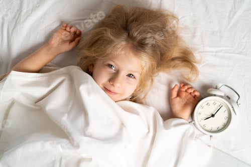 Preview: Smiling Girl Lying in Bed with Alarm Clock