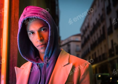 Preview: Young millennial hispanic man with red neon light reflection and a hood