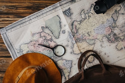 Preview: top view of brown leather bag, hat, magnifying glass and photo camera on map