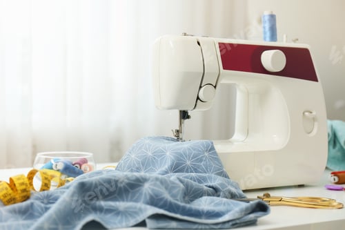 Preview: Modern sewing machine, fabric and accessories on table indoors