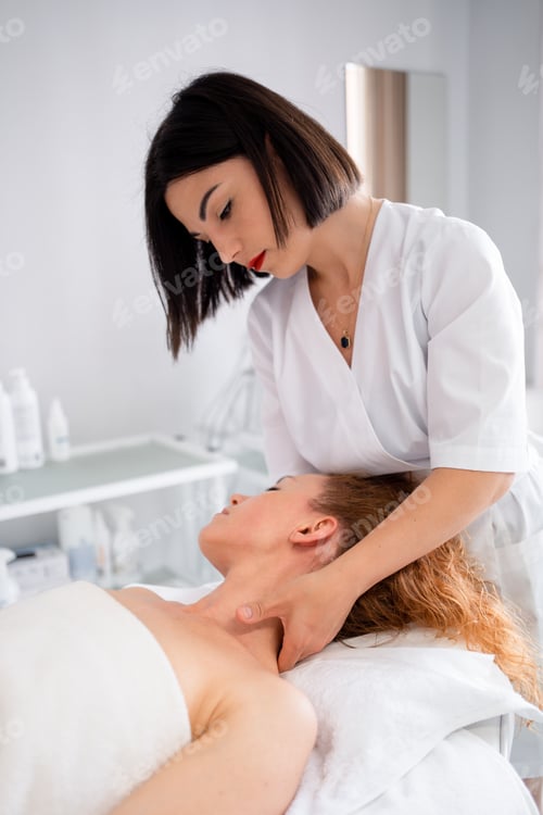 Vista previa: Beautician giving neck massage to woman lying on bed at beauty spa