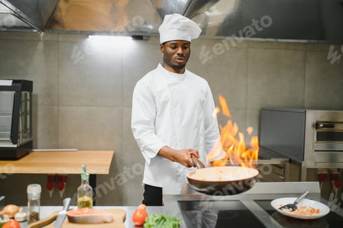 Preview: Cook cooking in kitchen with burning pan. Chef in the restaurant kitchen making flambe on frying pan