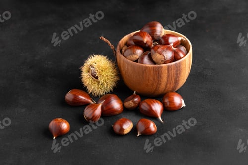 Preview: Fresh chestnuts in a wooden bowl on black background