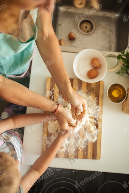 Preview: Top view of woman and little daughter making cookies while cooking on kitchen.