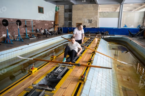 Preview: Group of swimmer athletes position properly for rowing simulator training in gym pool, aquatic sport