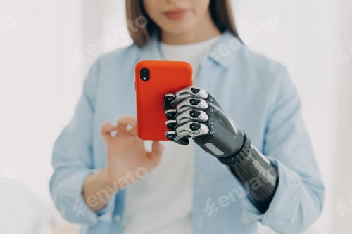 Preview: Hands of young european woman with smartphone. Girl holding the phone with bionic arm and texting.