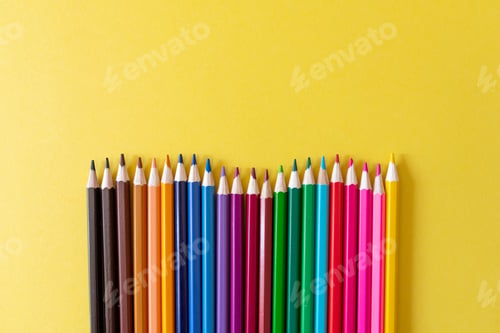 Preview: colourful pencils in row on yellow background with copy space