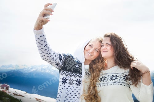 Preview: Happy sisters photographing a selfie in winter holidays