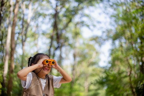 Preview: Happy Little Asian girls looking ahead and smiling child with the binoculars in the park.