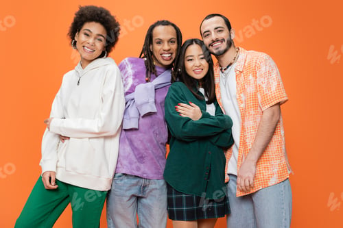 Preview: happy multiethnic friends wearing stylish clothes and posing isolated on orange