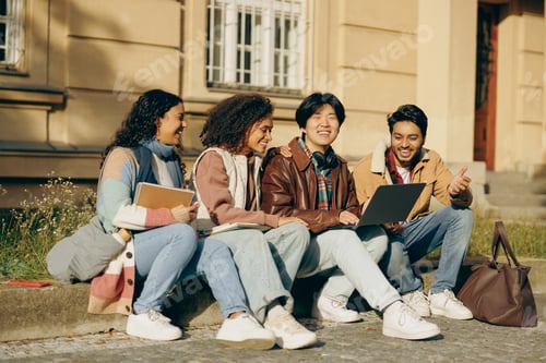 Preview: Smiling students with laptop is studying outdoors sitting near university. Education concept