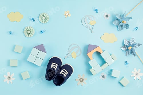 Preview: Cute newborn baby boy shoes with festive decoration over blue background. Baby shower, birthday