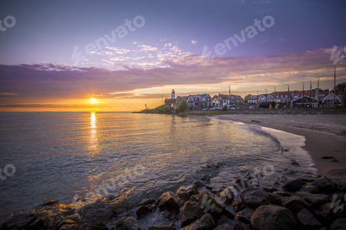 Preview: Beautiful shot of a colorful sunset sky by the lighthouse of Urk on the rocky beach at the lake