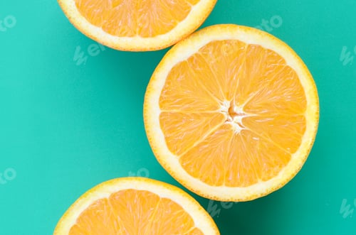 Preview: Top view of a several orange fruit slices on bright background in turquoise green color