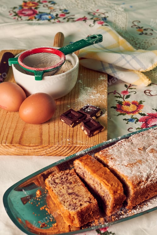 Preview: Homemade sponge cake on a white tablecloth with some ingredients: eggs, chocolate and flour