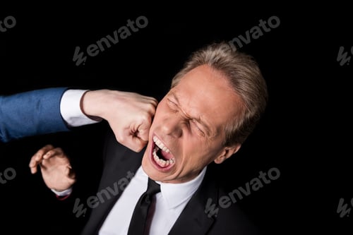 Preview: cropped shot of hand punching middle aged businessman isolated on black