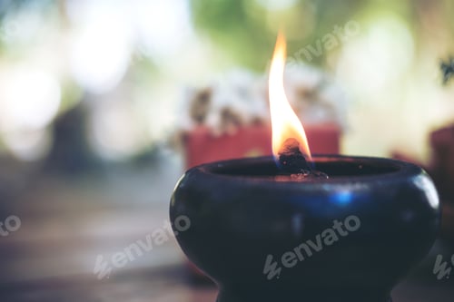 Preview: Candle flame in black earthen lamps on wooden table