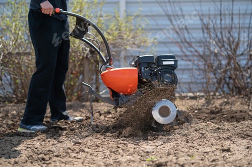Preview: a young man digs the ground in the garden with a motor-cultivator
