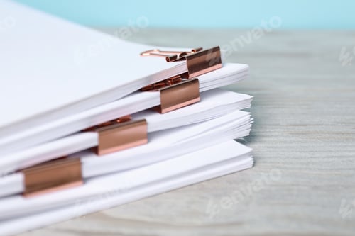 Preview: Binder clips with sheets of paper on wooden table, closeup