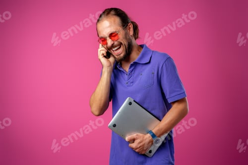 Preview: Man in glasses standing with laptop against pink background