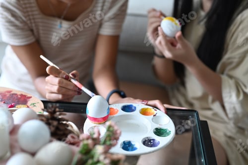 Preview: Young woman and her young sister coloring eggs, preparation for the Easter holiday.