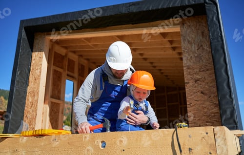 Preview: Father with toddler son building wooden frame house.